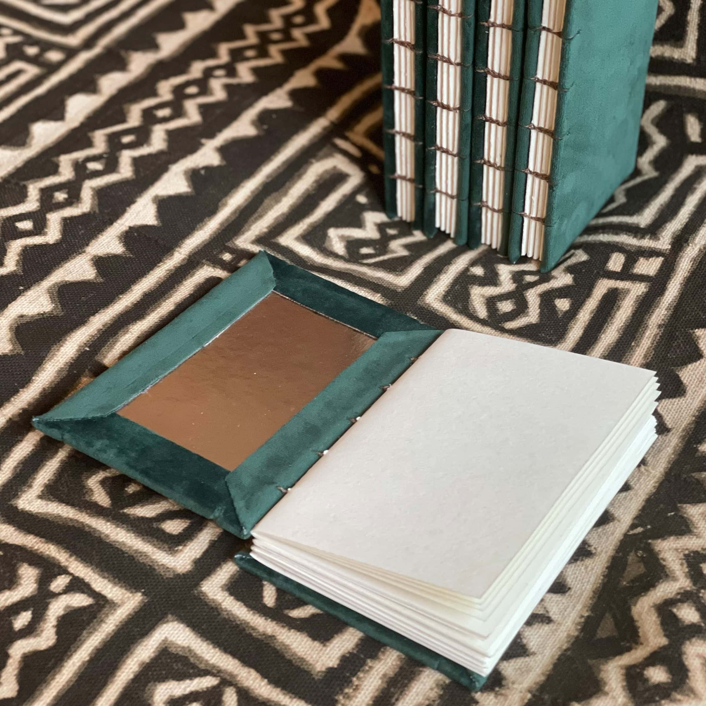 This is an image of handmade sketchbooks. This particular image features one book laying open flat on a surface to show the inside cover