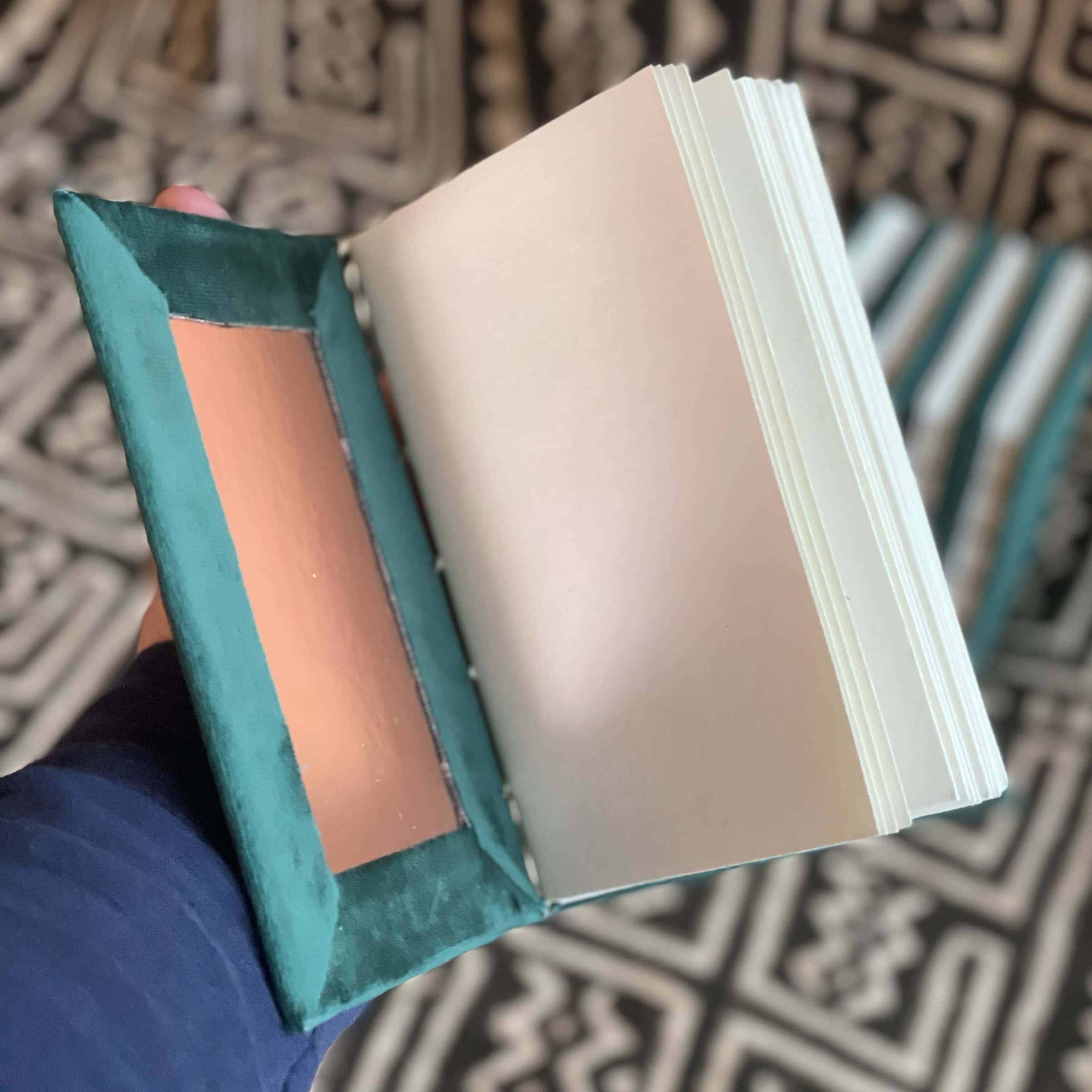 This is an image of handmade sketchbooks. This particular image features one book being held in the hands to show scale